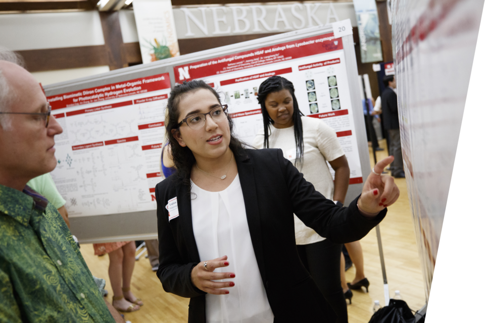 A woman presenting her poster at an economic conference.